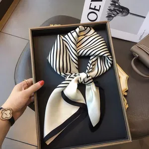 Detail of a luxury striped satin silk scarf displayed in a brown tray with artistic props