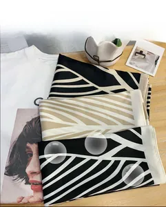 Detail of silk-like square scarves featuring geometric leaf patterns on a wooden surface