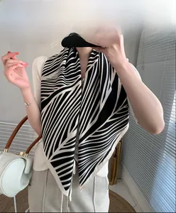Close-up of elegant black and white faux silk leaf print scarf held by a model