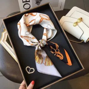 Detailed flat lay of silk square scarf with horse bridle pattern on a luxury black tray