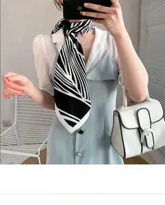 Detail of elegant black and white striped silk scarf paired with a white shirt and bag