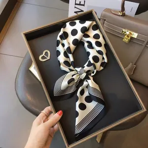 Detailed view of a vintage white silk scarf with black polka dots and striped edges