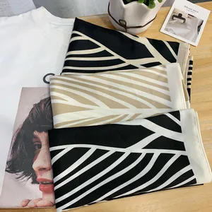 Close-up of geometric striped silk scarves folded on a white graphic tee for summer styling
