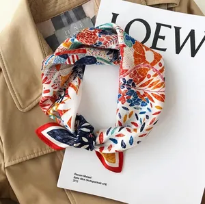 Detail of silk-feel floral scarf with abstract red and blue print on a stylish trench coat