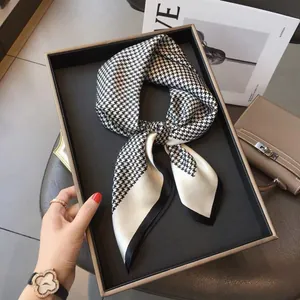 Classic black and white houndstooth silk scarf with satin finish on a display tray