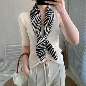 Detail of elegant black and white geometric silk scarf tied around model's neck