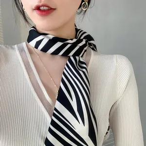 Close-up of zebra pattern silk scarf tied on neck with elegant jewelry and white knitwear