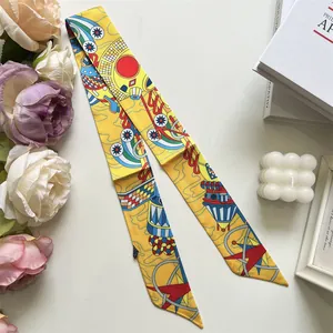 Détail d'un foulard étroit en soie jaune vif avec motifs abstraits et géométriques