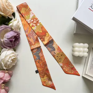 Detail of elegant orange zebra pattern silk twilly scarf with satin finish on lifestyle background