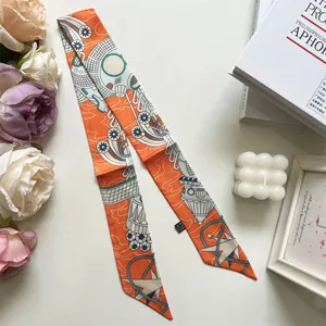 Détail macro d'un foulard étroit orange avec motifs géométriques et étiquette matière