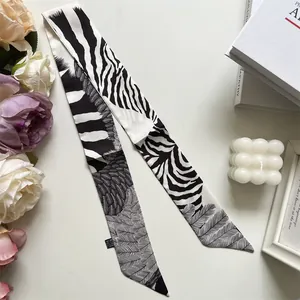 Detail of a black and white zebra pattern narrow silk scarf on a minimalist background