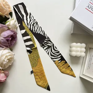 Detail of narrow silk scarf with zebra and golden feather patterns near white prop decor