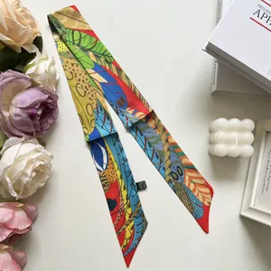 Close-up of narrow silk scarf with colorful feather print and detailed care label