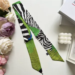 Detail of a narrow twilly scarf featuring zebra print and green palm leaf patterns