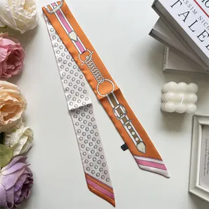 Detailed close-up of orange twilly scarf featuring horse bit and chain print patterns