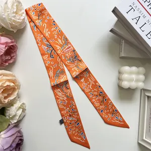 Detail of orange printed silk twilly scarf with abstract patterns and satin finish