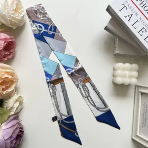 Detail of elegant navy geometric twilly silk scarf styled with lifestyle decor items