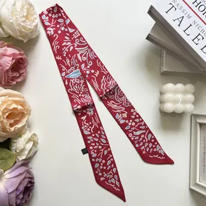 Detailed view of red patterned twilly scarf with abstract waves on white surface