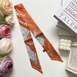 Detalle de pañuelo twilly de satén naranja con motivos de cadenas vintage y letras de Paris