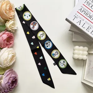 Close-up of black narrow silk scarf with fairy tale prints and heart pattern details