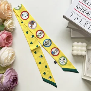 Detail of yellow silk scarf featuring whimsical fairy tale illustrations and heart patterns