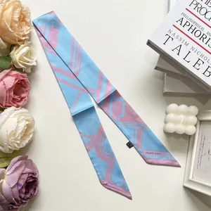 Dettaglio di un foulard sottile in seta con motivi geometrici blu e rosa e testo Paris