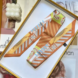 Silk twilly scarf with geometric patterns in orange and yellow, presented in a gift box