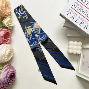 Dettaglio di un elegante foulard twilly blu reale con carrozze dorate e stampa parigina