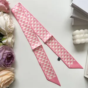Detail van roze-witte zijden sjaal met geometrisch patroon als handtasaccessoire