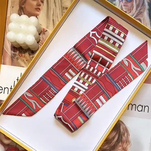 Détail d'un twilly en soie rouge à motifs géométriques dans son coffret cadeau de luxe