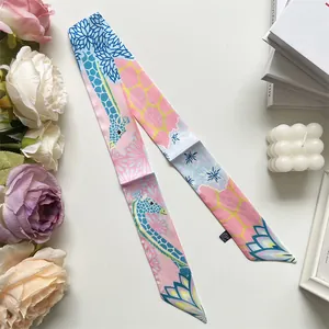 Close-up of pink silk-like twilly scarf with giraffe patterns and 100% polyester label