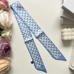 Detailopname van blauwe zijden sjaal met geometrische driehoekspatronen op een witte tafel