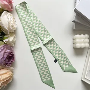 Detailopname van een groene zijden sjaal met witte geometrische driehoekspatronen