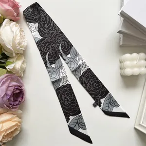 Détail du foulard en soie synthétique à imprimé camélia noir et blanc pour anse de sac