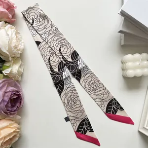 Détail d'un twilly en soie avec motif de camélia et touches de rose vif sur les pointes