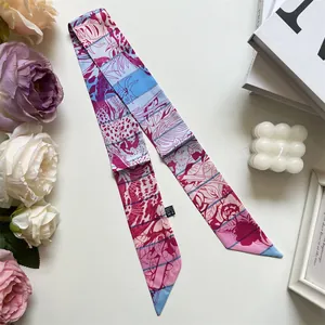 Détail d'un foulard twilly à fleurs roses et bleues avec accessoires décoratifs