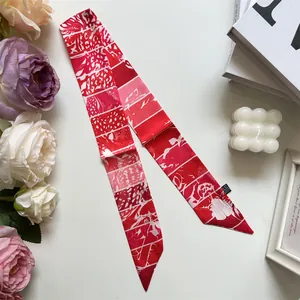 Détail d'un foulard en soie rouge à motif floral élégant sur un fond blanc épuré