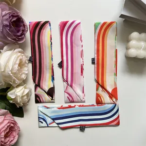 Detailed flat lay of colorful patterned narrow silk scarves with floral and candle props