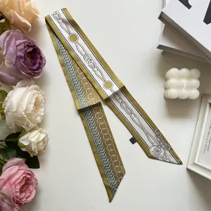 Détail d'un foulard élégant vert olive et blanc avec motifs géométriques et étiquette