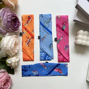 Vista cenital de bufandas twilly con estampado de París en naranja y azul sobre blanco