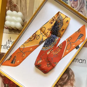 Elegant orange and yellow printed silk twilly scarf in a gift box with chain patterns