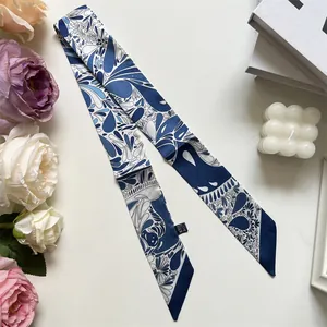 Macro detail of navy and white paisley silk scarf hair tie with washing label on a desk