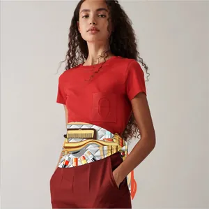 Close-up of silk scarf with cosmetic tool patterns tied around red high-waist trousers