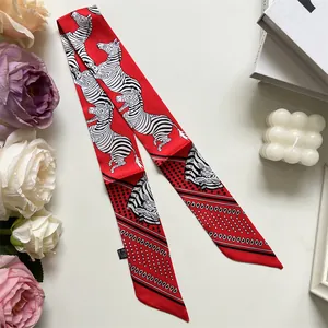 Detail of red twilly silk scarf with zebra print and geometric patterns on white surface