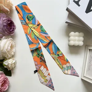 Detalle de pañuelo twilly de seda con estampado naranja y azul y adornos florales