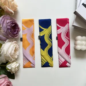 Detail of three twilly scarves with geometric patterns on a decorative floral background