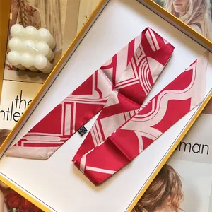 Elegant red and pink geometric silk twilly scarf neatly displayed in a premium gift box