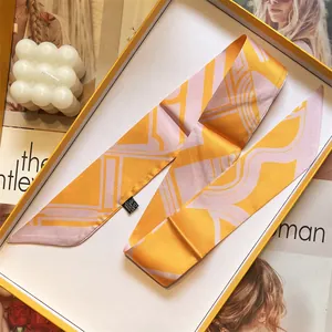 Elegant geometric silk twilly scarf in orange and purple tones within a yellow gift box