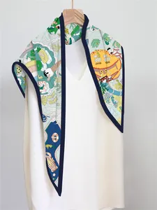 Detail of printed silk scarf with beach illustrations hanging on a wooden hanger