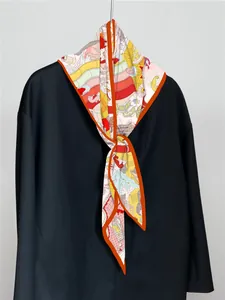 Detailed view of colorful printed silk scarf with bright orange border on black coat